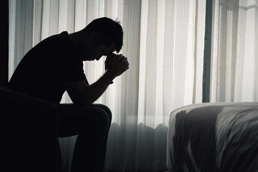 Depressed man sitting on  side of bed