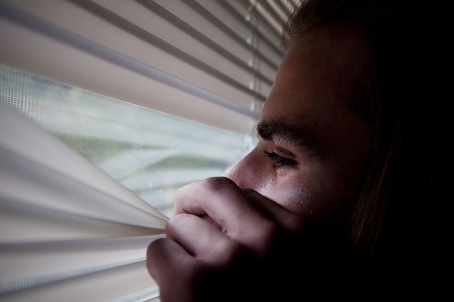 Man peeking out window blinds