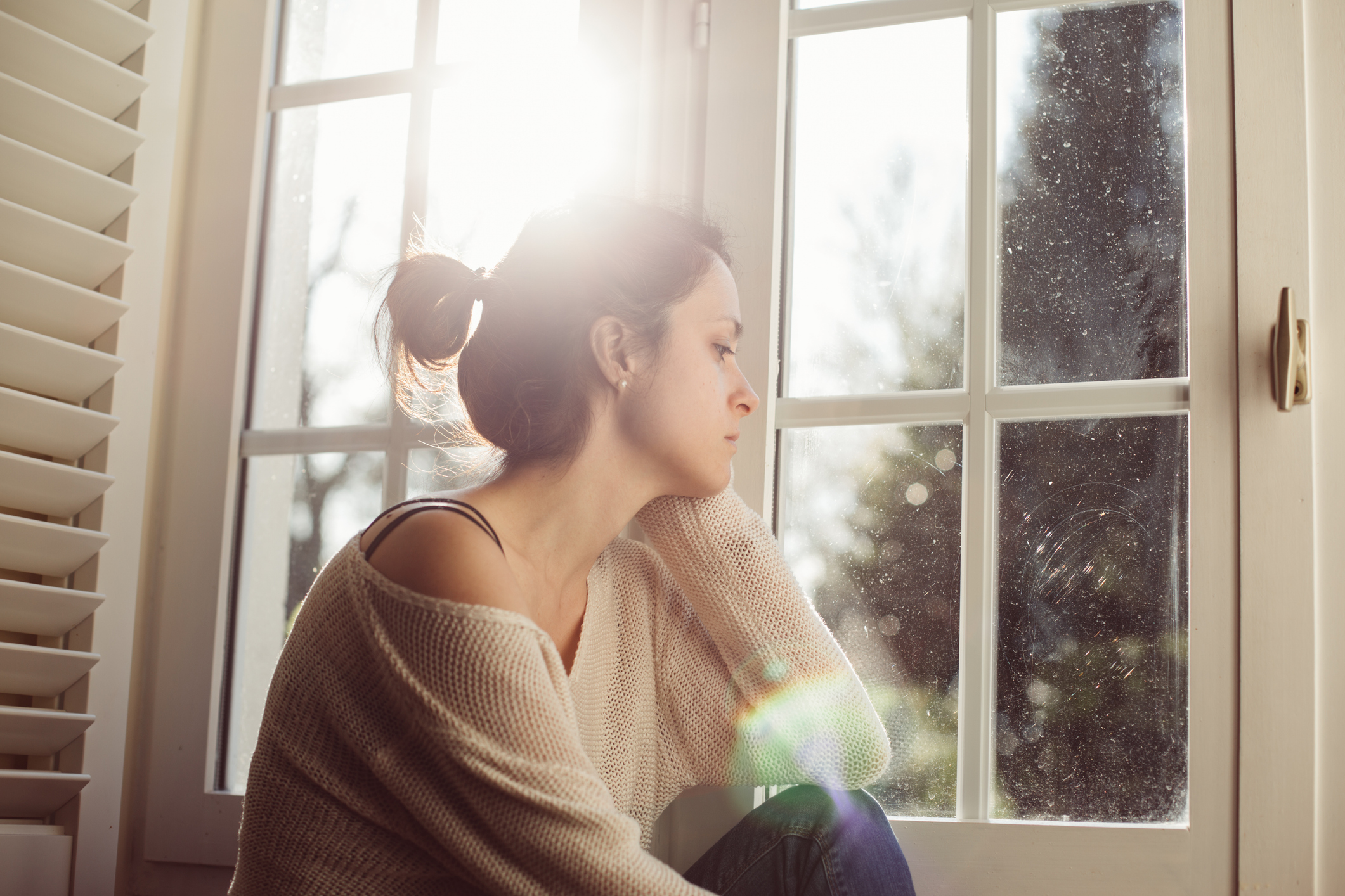 Unhappy housewife sitting near the window